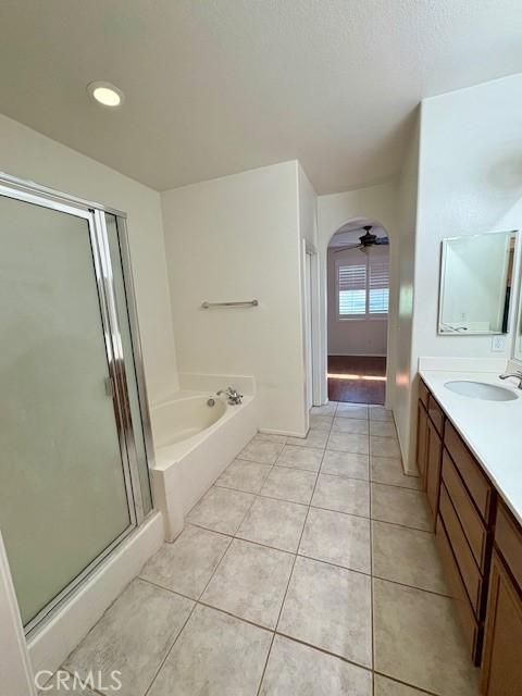 bathroom with a textured ceiling, tile patterned floors, ceiling fan, independent shower and bath, and vanity