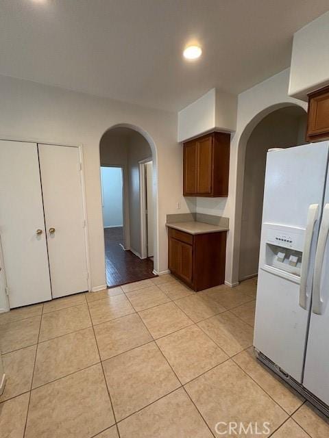 kitchen featuring white refrigerator with ice dispenser and light tile patterned floors