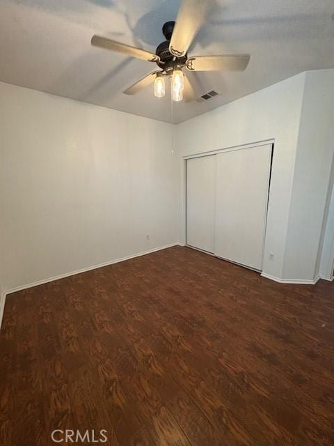 unfurnished bedroom featuring a closet, ceiling fan, and dark hardwood / wood-style flooring