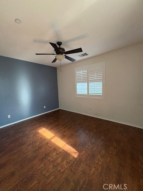 empty room featuring ceiling fan and dark wood-type flooring