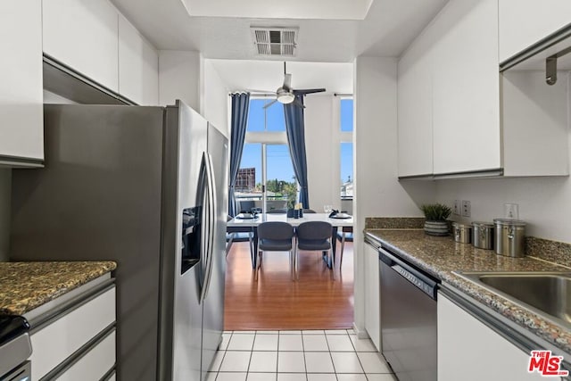 kitchen with dishwasher, stainless steel fridge with ice dispenser, light tile patterned floors, ceiling fan, and white cabinetry