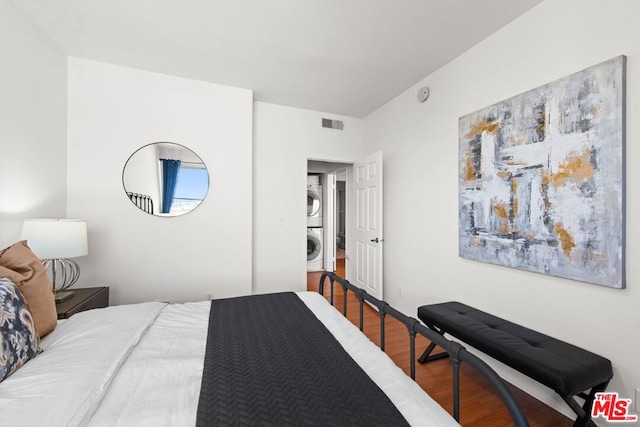 bedroom featuring stacked washer / drying machine and hardwood / wood-style floors