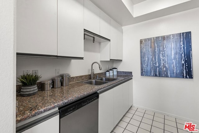 kitchen with dark stone countertops, light tile patterned floors, sink, white cabinetry, and stainless steel dishwasher