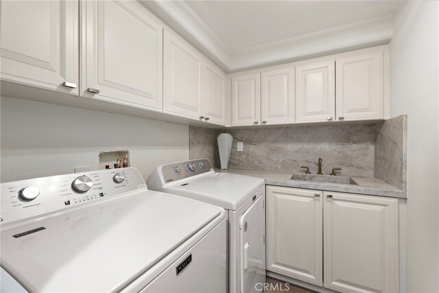 clothes washing area featuring sink, cabinets, and washer and clothes dryer