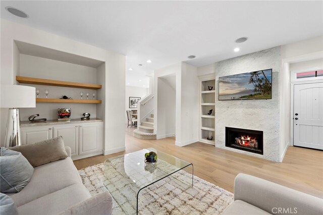 living room with light wood-type flooring, built in features, and a fireplace