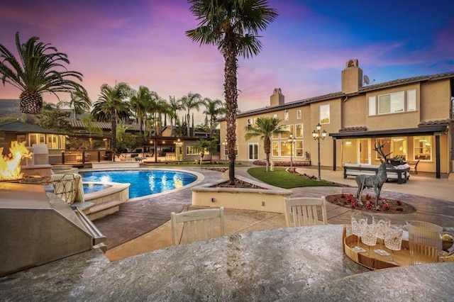 pool at dusk featuring a patio area