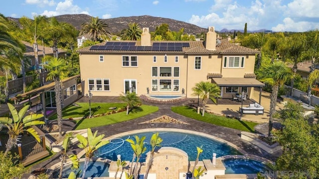 back of house with a pool with hot tub, a patio area, and a mountain view