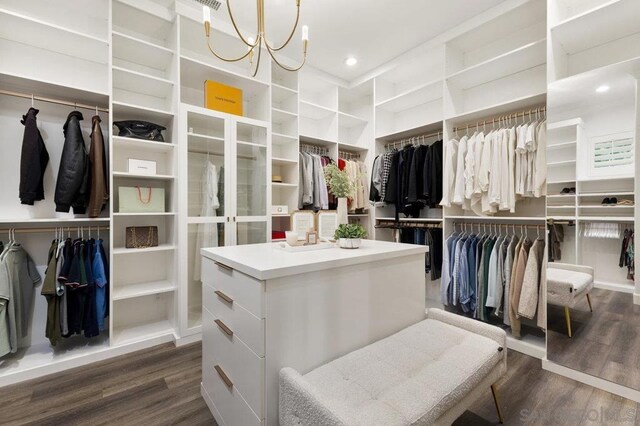 walk in closet with a notable chandelier and dark hardwood / wood-style floors