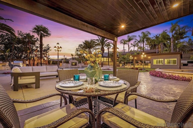 patio terrace at dusk with an outdoor living space with a fireplace