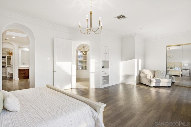 bedroom featuring ensuite bath, an inviting chandelier, crown molding, and dark hardwood / wood-style flooring