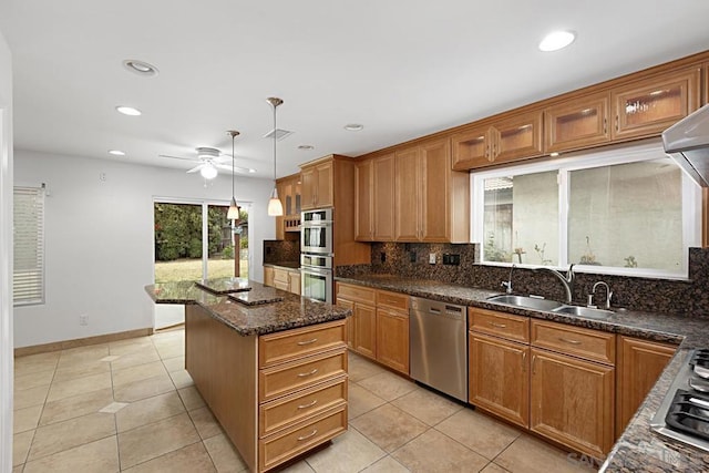 kitchen featuring ceiling fan, stainless steel appliances, a kitchen island, pendant lighting, and sink