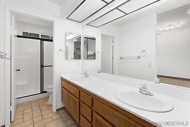 bathroom featuring toilet, vanity, tile patterned flooring, and a shower with door