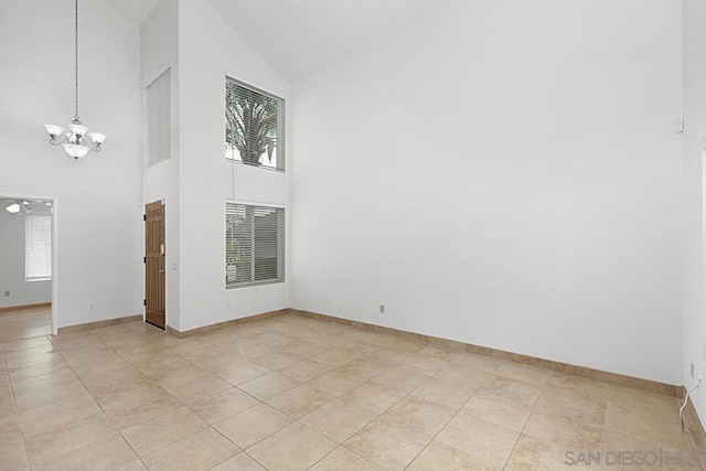 tiled empty room featuring high vaulted ceiling and ceiling fan with notable chandelier