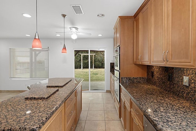 kitchen with ceiling fan, backsplash, pendant lighting, light tile patterned floors, and dark stone counters