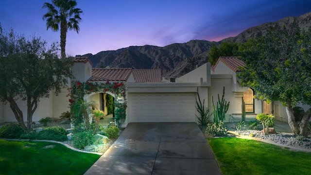 view of front of property featuring a garage, a mountain view, and a lawn