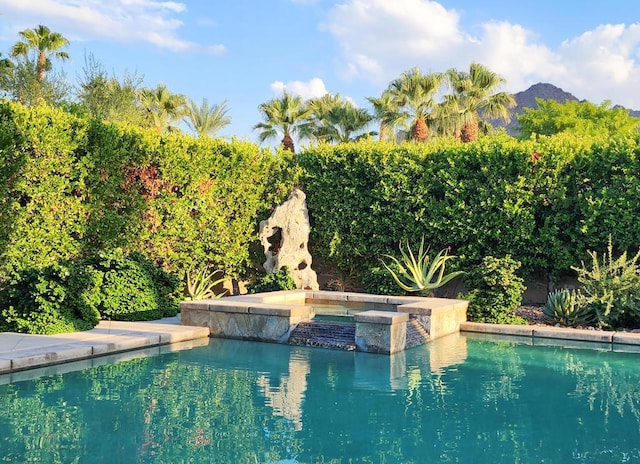 view of swimming pool with an in ground hot tub and a mountain view