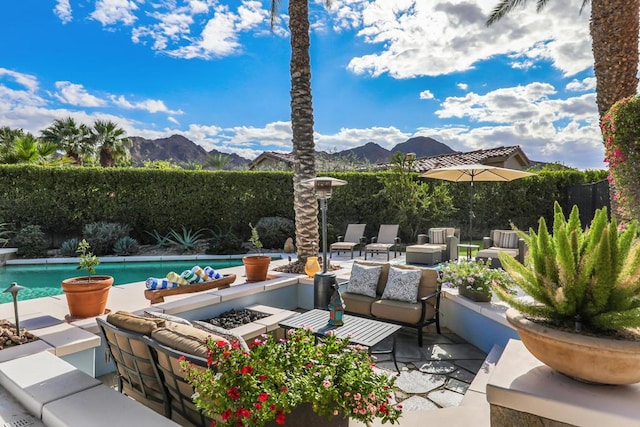 view of patio with a fenced in pool, a mountain view, and an outdoor living space with a fire pit