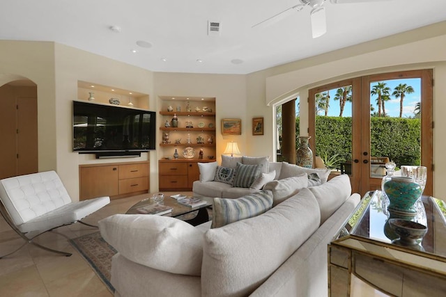 tiled living room featuring built in features, ceiling fan, and french doors