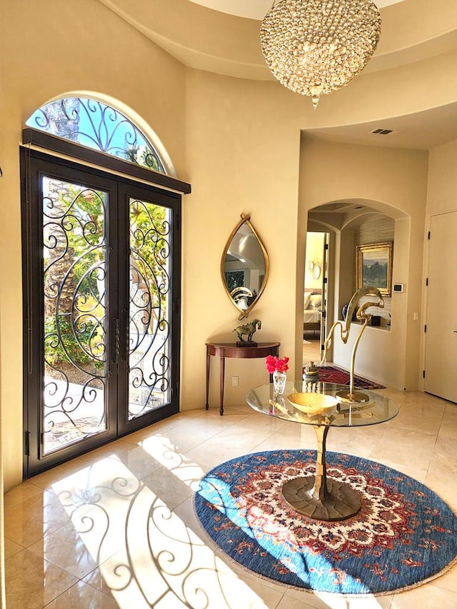 foyer with french doors, a chandelier, and a high ceiling