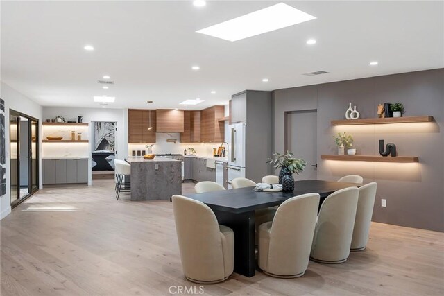 dining space with a skylight and light wood-type flooring