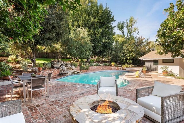 view of swimming pool with an outdoor fire pit and a patio