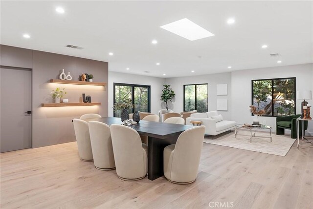 dining space featuring light wood-type flooring and a skylight