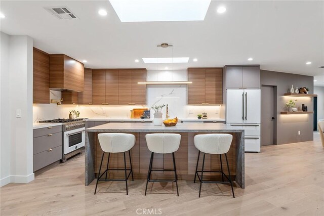 kitchen featuring a breakfast bar area, light wood-type flooring, white fridge, and stainless steel stove