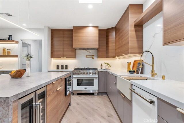 kitchen with white dishwasher, wine cooler, ventilation hood, gas range, and light hardwood / wood-style flooring