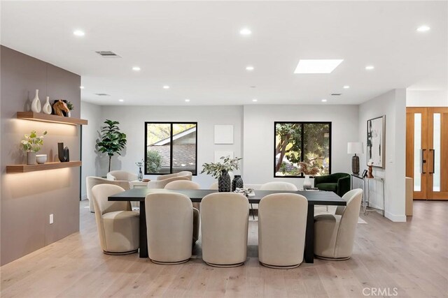 dining area featuring light wood-type flooring and a skylight