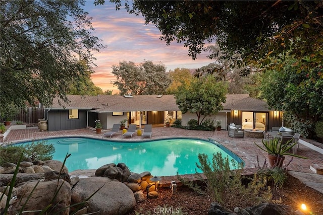 pool at dusk with a patio area