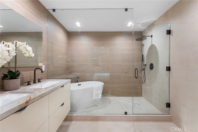 bathroom featuring plus walk in shower, tile patterned flooring, tile walls, and vanity