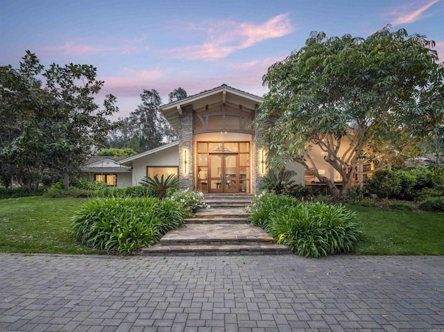 exterior entry at dusk featuring french doors and a yard