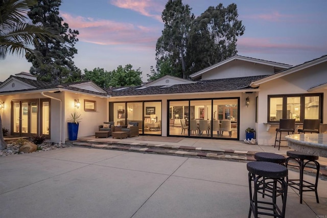 back house at dusk featuring a patio