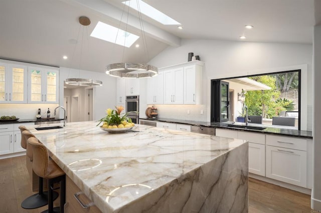 kitchen featuring sink, hanging light fixtures, a large island with sink, and tasteful backsplash