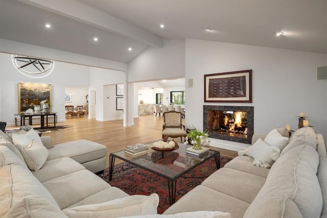 living room with high vaulted ceiling, a premium fireplace, beam ceiling, and light hardwood / wood-style floors