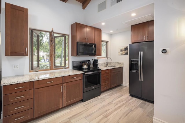 kitchen featuring black fridge with ice dispenser, sink, light stone counters, light hardwood / wood-style floors, and electric stove