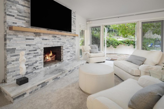 living room featuring a stone fireplace and carpet flooring