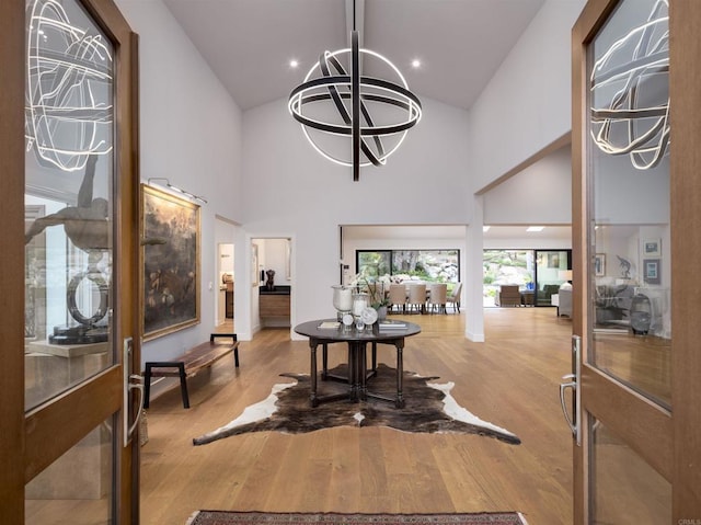 entrance foyer with high vaulted ceiling, a chandelier, and light hardwood / wood-style floors