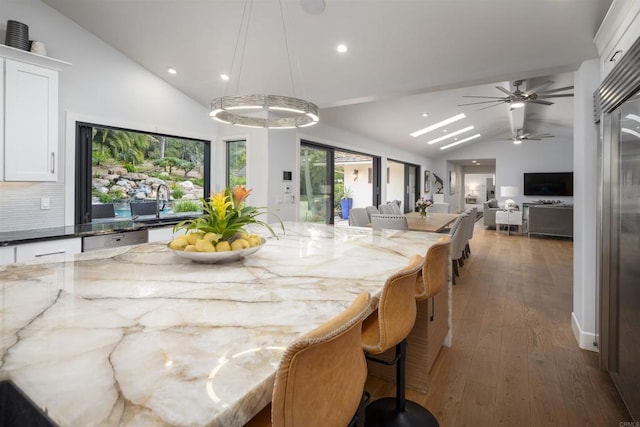 kitchen featuring a kitchen bar, white cabinetry, dark stone countertops, and hanging light fixtures