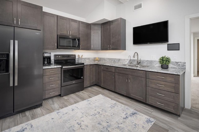 5041 El Secreto, Rancho Santa Fe, CA 92067 - kitchen featuring stainless steel appliances, a sink, light wood-type flooring, vaulted ceiling, and light stone countertops