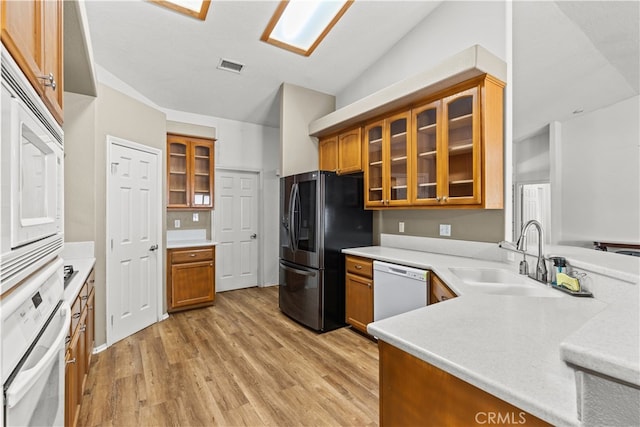 kitchen featuring lofted ceiling, light wood-type flooring, sink, and white appliances