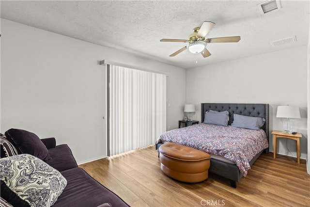 bedroom featuring ceiling fan, wood-type flooring, and a textured ceiling