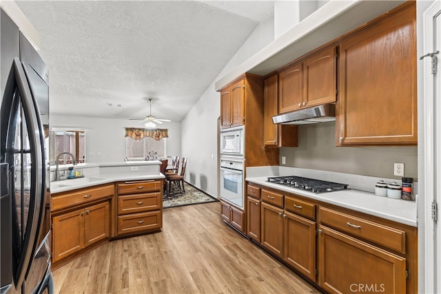 kitchen featuring white appliances, sink, vaulted ceiling, ceiling fan, and light hardwood / wood-style flooring