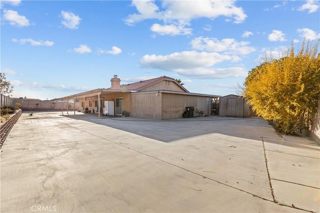 view of home's exterior with a storage shed and a patio