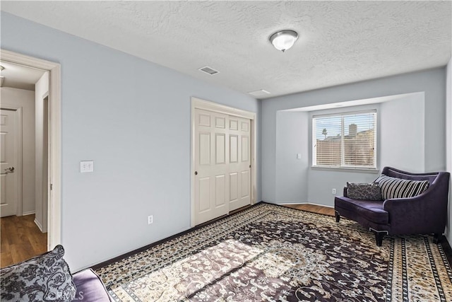 living area featuring a textured ceiling and hardwood / wood-style flooring