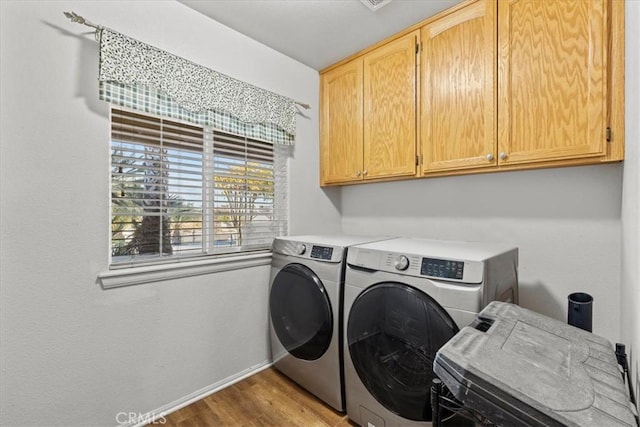 washroom featuring cabinets, light hardwood / wood-style flooring, and washing machine and clothes dryer