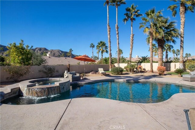 view of pool with an in ground hot tub, a patio area, pool water feature, and a mountain view