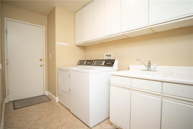 laundry area with cabinets, light tile patterned floors, independent washer and dryer, and sink