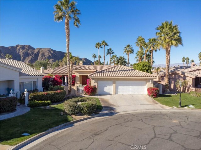 mediterranean / spanish house featuring a mountain view, a front lawn, and a garage