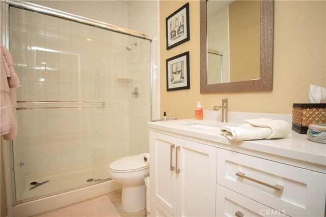 bathroom featuring a shower with shower door, vanity, and toilet